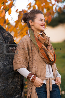 Portrait of relaxed woman near stone rock in evening autumn park