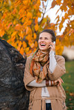 Young woman talking cell phone in autumn outdoors in evening