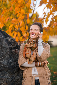 Young woman talking cell phone in autumn outdoors in evening
