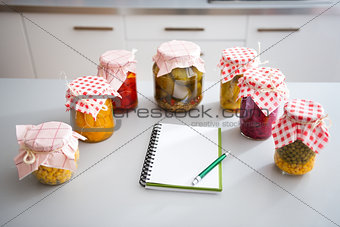 Jars of preserved vegetables on kitchen counter with notepad