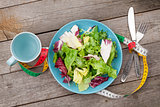 Plate with fresh salad, measure tape, cup, knife and fork. Diet 