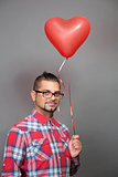 Handsome hipster man with red heart baloon in studio