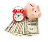 Piggy bank with money and alarm clock, side view
