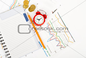 Red alarm clock with notebook and pencil
