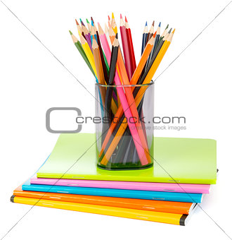 Pencil cup with crayons on copybooks