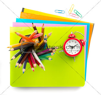 Crayons and alarm clock on copybooks