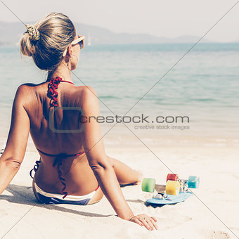 sexy suntanned lady with the blue penny board rests on the beach