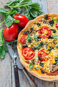 Pizza with mushrooms, tomatoes and basil.
