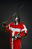 Medieval knight with sword and shield against gray wall