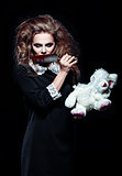 Horror shot: scary monster girl with torn rabbit toy and bloody knife in hands