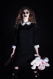 Horror shot: strange gothic girl with torn rabbit toy and bloody knife in hands