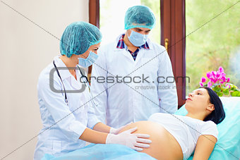 doctor palpates the abdomen of pregnant woman during childbirth