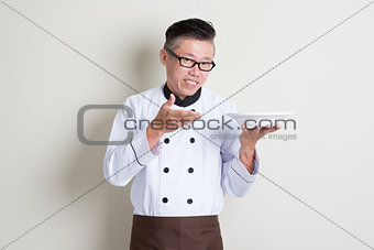 Mature Asian Chinese chef presenting dish