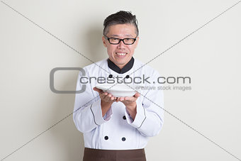 Mature Chinese chef presenting dish