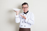 Mature Asian chef presenting dish