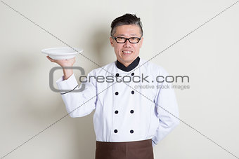 Mature Asian Chinese chef holding a dish