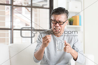 Mature Asian Chinese man eating medicine
