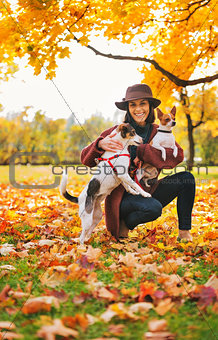 Young woman with two dogs playing outside in autumn leaves