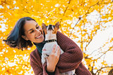 Portrait of young happy woman with little cute dog in park