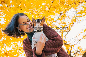 Portrait of young happy woman with little cute dog in park