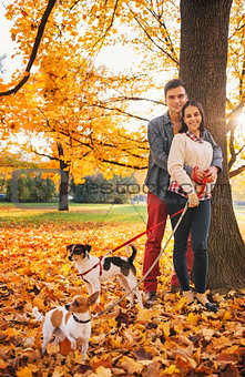 Portrait of couple with two little dogs on the walk in park