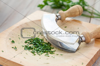 Fresh parsley on a board with mezzaluna 