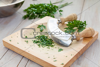 Fresh parsley on a board with mezzaluna 