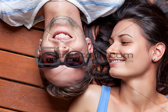Happy young couple lying on a wooden floor