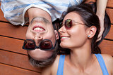 Happy young couple lying on a wooden floor