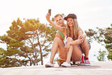 Happy couple with sitting on skateboard and taking a selfie 