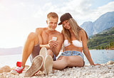 Couple sitting on a beach and taking a selfie
