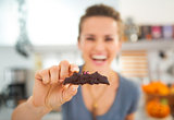 Closeup on Halloween bat biscuit in hand of smiling young woman