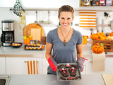 Happy housewife holding tray with baked Halloween biscuits