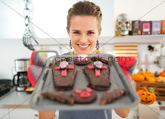 Smiling housewife showing off freshly baked Halloween biscuits