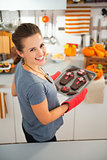 Woman removing from oven tray with homemade Halloween cookies