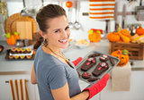 Housewife removing from oven tray with Halloween biscuits