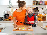Halloween dressed girl with mother cutting out cookies