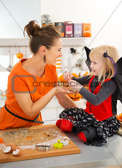 Halloween dressed girl with mother holding uncooked biscuits