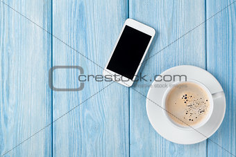 Coffee cup and smartphone on wooden table background