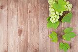 Bunch of white grapes with leaves on wood