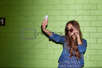 beautiful long-haired woman with a smartphone near a green brick
