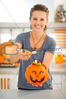 Woman holding halloween bucket and giving trick or treat candy
