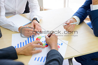 Business People Analyzing Financial Results on Graphs around the Table in Modern Office. Team Work Concept