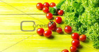 lettuce salad, tomatoes and chives on wooden green background.