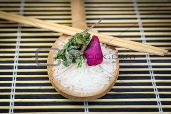 Rice on wooden spoon with wooden chopsticks