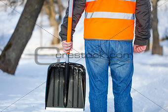 Man with a snow shovel on the sidewalk in winter