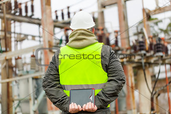 Electrician with tablet PC in electrical substation