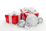 Christmas baubles and red gift boxes over snow