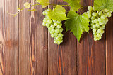 Bunch of white grapes with leaves on wood