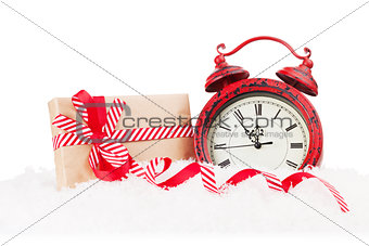 Christmas gift box and alarm clock in snow